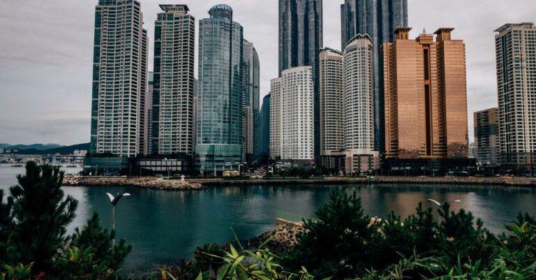 A breathtaking view of urban skyscrapers reflecting in a serene waterfront, showcasing modern architecture and a bustling city life.